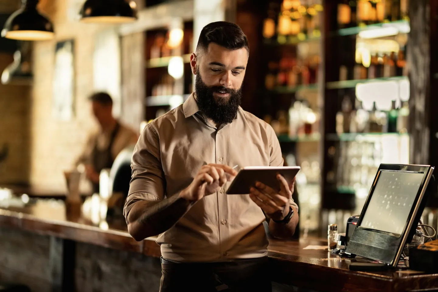 Dono de restaurante com tablet em mãos dentro do salão